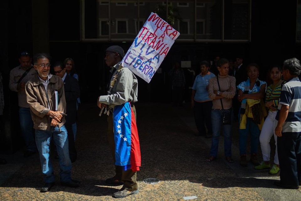 Um homem segura um cartaz dizendo "Morte à tirania. Viva a liberdade", do lado de fora do prédio da Assembleia Nacional em Caracas , Venezuela | FEDERICO PARRA/AFP