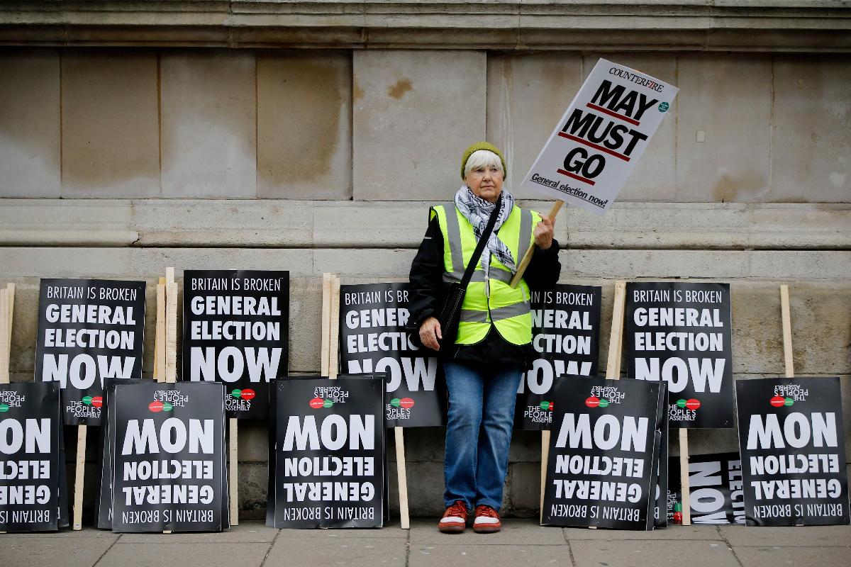 Uma mulher segura um cartaz que diz “May deve sair” durante uma manifestação no centro de Londres, em 12 de janeiro. Ao lado dela estão diversos cartazes que pedem pela convocação de uma eleição geral | TOLGA AKMEN/AFP