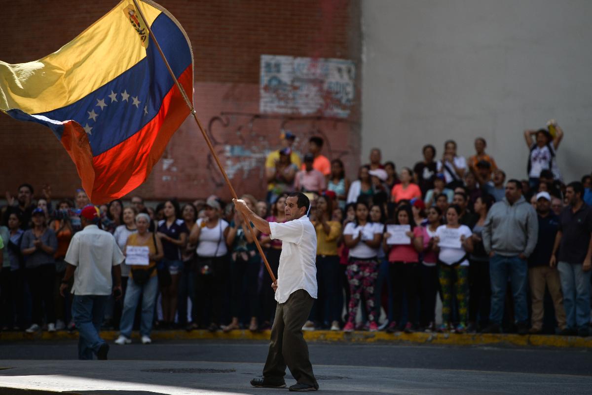 Manifestante agita a bandeira da Venezuela durante protesto contra o regime de Maduro, 30 de janeiro | FEDERICO PARRA / AFP