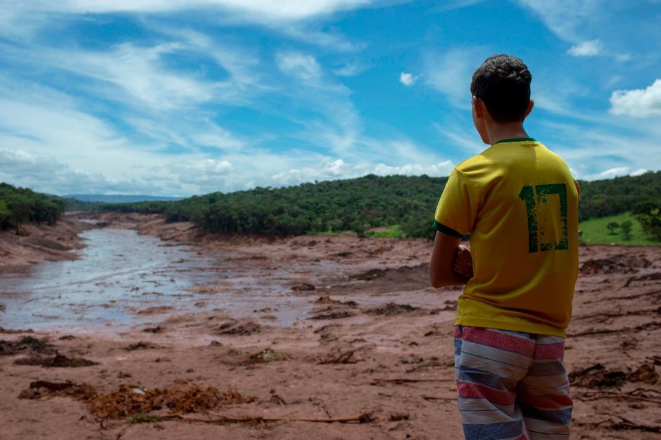 Menino olha para uma área da comunidade de Casa Grande, afetada pelo lodo após o colapso, há dois dias, de uma barragem em uma mina de minério de ferro pertencente à gigante mineradora Vale, perto da cidade de Brumadinho (MG) | MAURO PIMENTEL/AFP