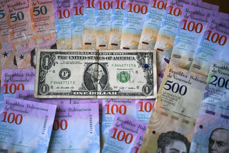 Cédulas de bolívares e uma nota de um dólar. O valor da moeda venezuelana caiu quase 35% nesta segunda-feira | YURI CORTEZ / AFP