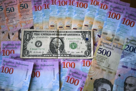 Cinco gráficos que explicam a crise da Venezuela Cédulas de bolívares e uma nota de um dólar. O valor da moeda venezuelana caiu quase 35% nesta segunda-feira | YURI CORTEZ / AFP