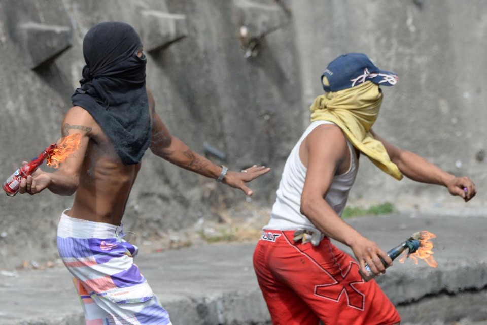 Manifestante jogam coquetéis Molotov durante confrontos com policiais nos arredores de um posto de comando da Guarda Nacional em Cotiza, no norte de Caracas, em 21 de janeiro de 2019 | FEDERICO PARRA/AFP