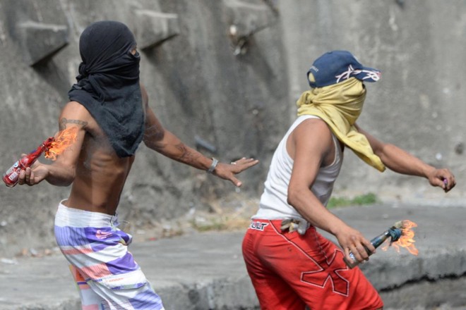 Manifestante jogam coquetéis Molotov durante confrontos com policiais nos arredores de um posto de comando da Guarda Nacional em Cotiza, no norte de Caracas, em 21 de janeiro de 2019 | FEDERICO PARRA/AFP