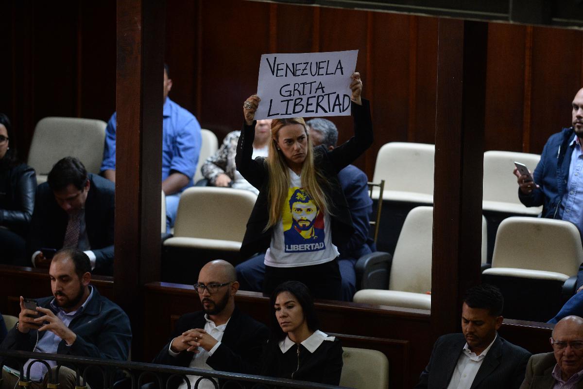 A ativista Lilian Tintori, esposa do líder da oposição venezuelana Leopoldo Lopez - que atualmente está em prisão domiciliar - exibe um cartaz que diz “Venezuela grita por liberdade”, em sessão da Assembleia Nacional | FEDERICO PARRA/AFP