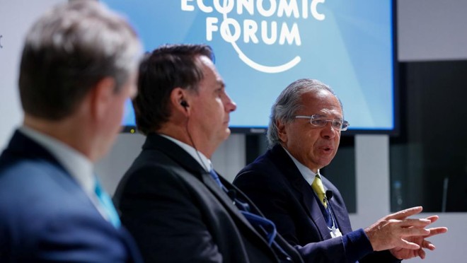O ministro Paulo Guedes ao lado do presidente Jair Bolsonaro em reunião do Conselho Internacional de Negócios em Davos, na terça (22). Em outro evento, fechado, o ministro da Economia anunciou simplificação de impostos mas também a retomada de taxações. | Alan Santos/PR
