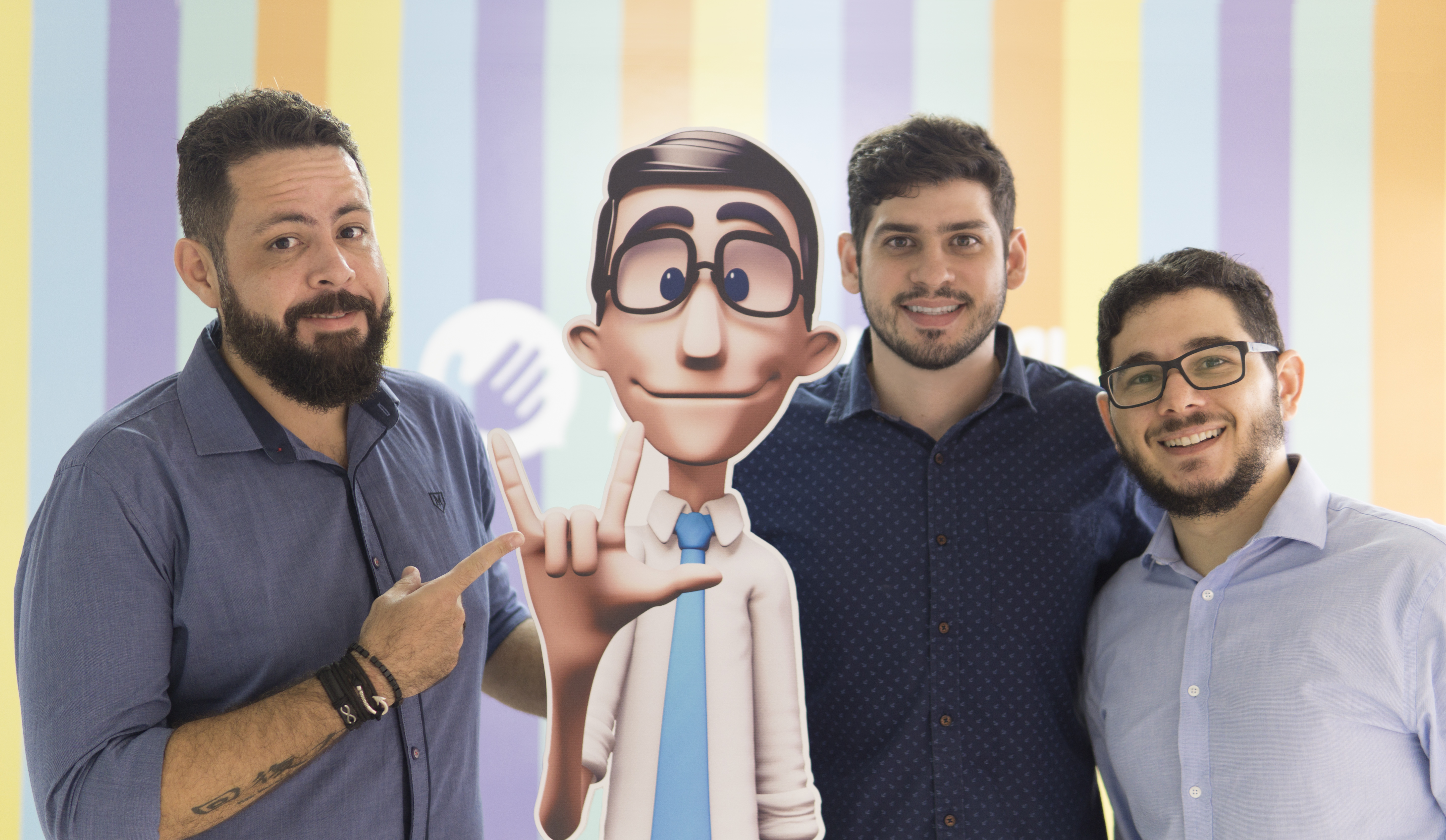 Carlos Wanderlean, Ronaldo Tenório e Thadeu Luz, fundadores da Hand Talk, ao lado da imagem do intérprete virtual da empresa, Hugo. | Divulgação/