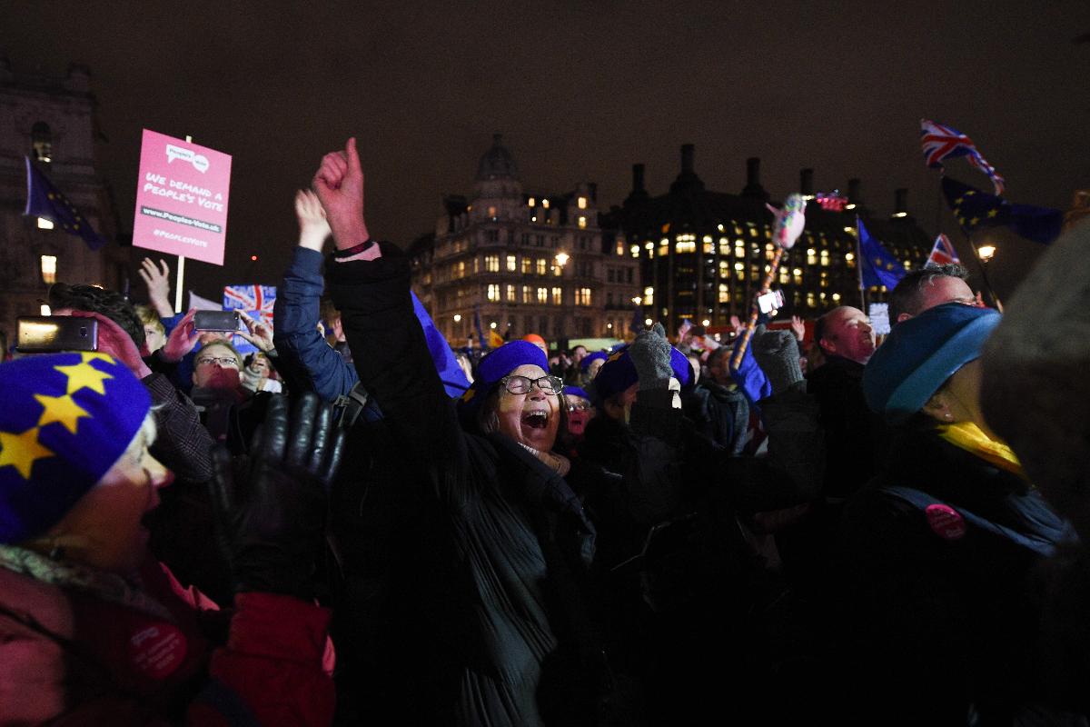 Pessoas reagem ao resultado da votação sobre o acordo do Brexit no Parlamento britânico | OLI SCARFF / AFP