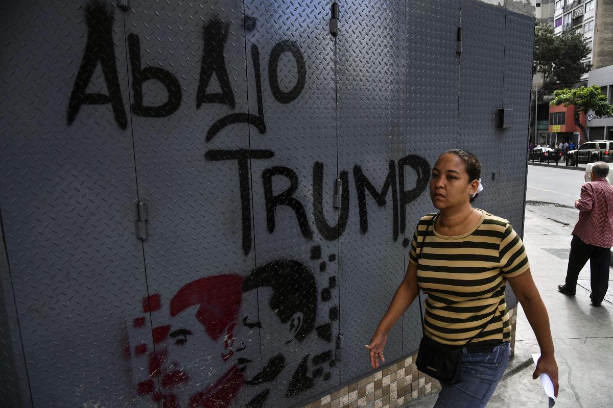 Muro com a imagem do ex-presidente venezuelano Hugo Chávez e os dizeres "Fora Trump", em Caracas, 24 de janeiro | YURI CORTEZ / AFP