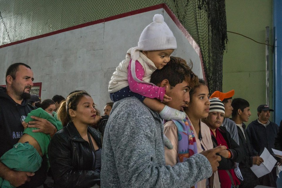 Migrantes aguardam serem chamados por oficiais da imigração em um centro temporário em que agências estaduais e federais têm ajudado os migrantes a solicitar legalização de status e encontrar empregos, em Tijuana | MAURICIO LIMA / 
NYT