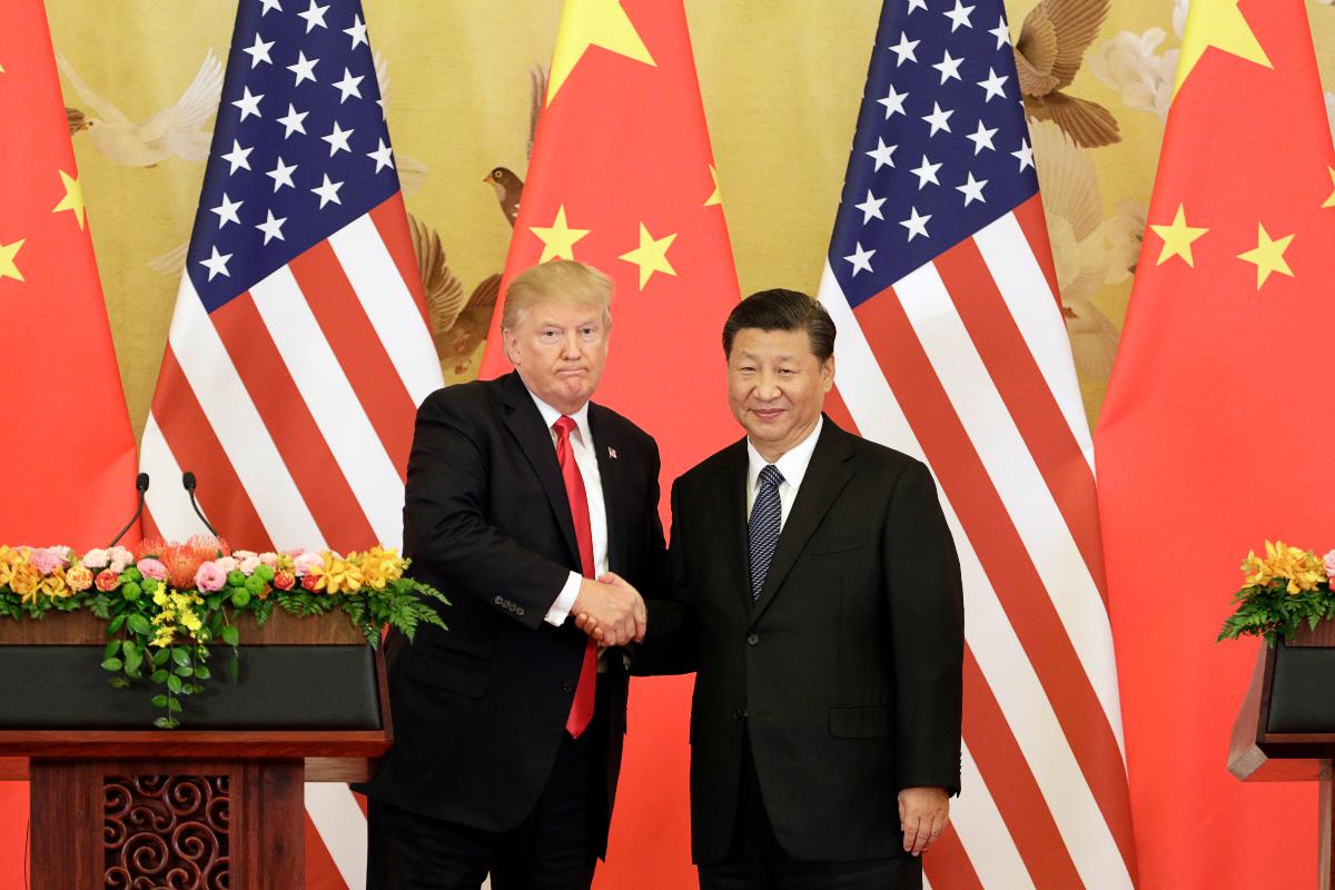 O presidente dos EUA, Donald Trump, e o presidente da China, Xi Jinping, se cumprimentam durante encontro em Pequim, 9 de novembro de 2017 | Qilai Shen / Bloomberg
