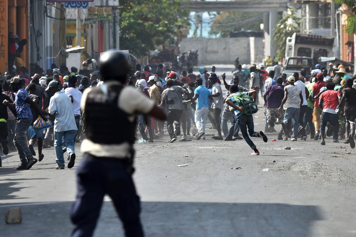 Manifestantes fogem quando a polícia abre fogo durante protestos no centro da capital haitiana, Porto Príncipe, 13 de fevereiro. | HECTOR RETAMAL / AFP