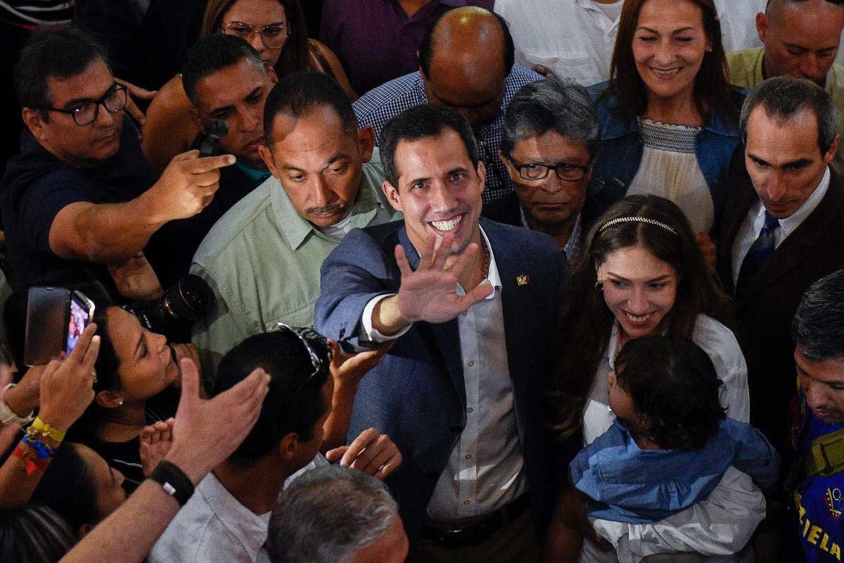 O presidente interino da Venezuela Juan Guaidó acena ao lado de sua esposa, Fabiana Rosales e de sua filha, Miranda, após sair de uma missa em Caracas, 10 de fevereiro | FEDERICO PARRA / AFP