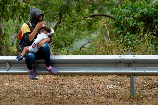Enquanto segue o impasse sobre a entrada de ajuda humanitária, milhares de venezuelanos deixam diariamente o país. Na foto, uma mulher e uma criança descansam no caminho entre Cúcuta e Pamplona, na Colômbia, em 10 de fevereiro de 2019 | RAUL ARBOLEDA/AFP