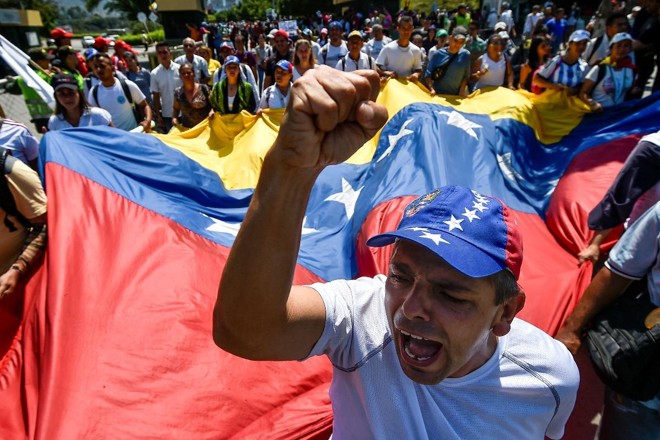 Venezuelanos participam de um protesto contra Nicolas Maduro na ponte internacional Simon Bolivar em Cúcuta, na Colômbia, na fronteira com a Venezuela, em 15 de fevereiro de 2019 | LUIS ROBAYO/AFP