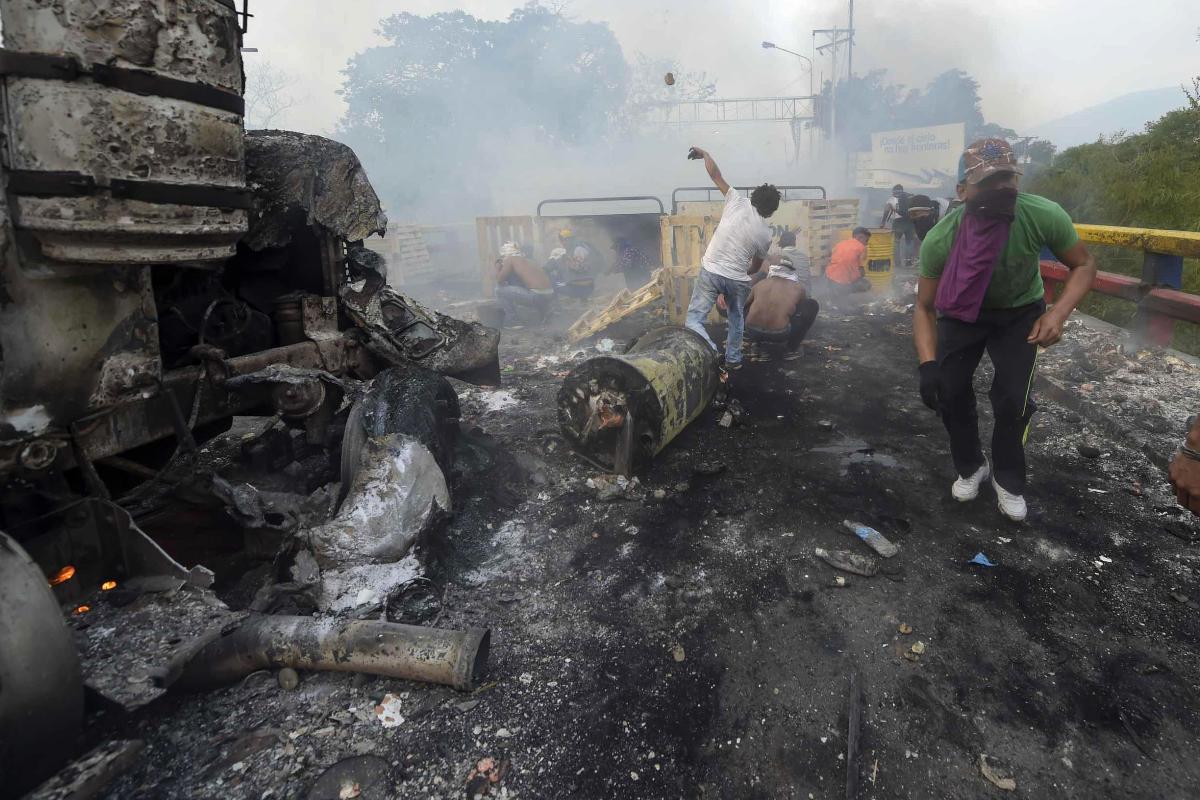 Manifestantes atiram pedras após um caminhão com ajuda humanitária ter sido incendiado na ponte entre a cidade colombiana de Cúcuta e Ureña, na Venezuela. | RAUL ARBOLEDA / AFP