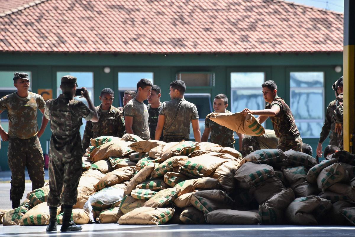 Soldados brasileiros empilham ajuda humanitária depois de descarregá-la de um avião da Força Aérea Brasileira, em Boa Vista | NELSON ALMEIDA/AFP