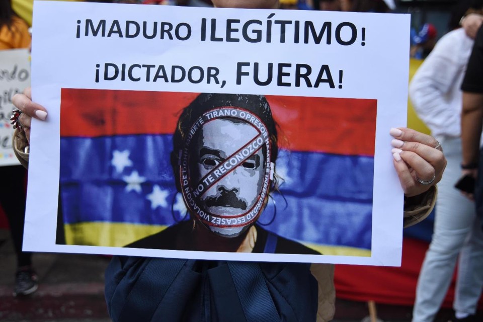 Mulher segura um cartaz dizendo "Maduro, ilegítimo, fora ditador" durante um protesto de venezuelanos na embaixada da Venezuela na Cidade da Guatemala | ORLANDO ESTRADA/AFP