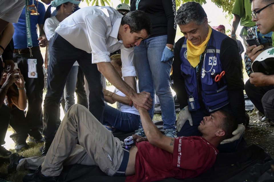 Juan Guaido cumprimenta um voluntário do movimento "Ajuda e Liberdade da Coalizão Venezuela", que desmaiou durante uma manifestação em Caracas | YURI CORTEZ/AFP