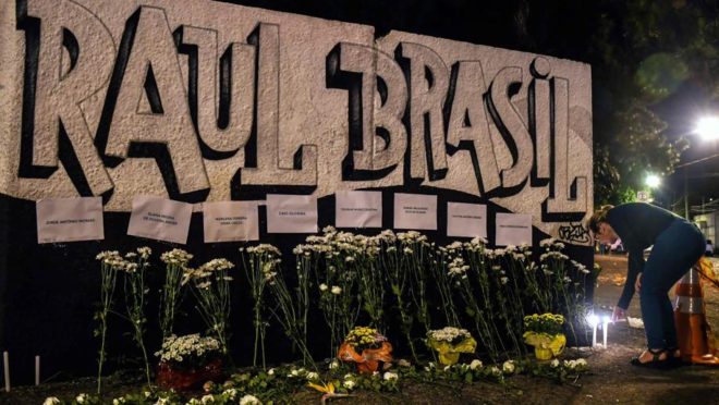 Uma mulher acende uma vela em frente à escola pública Raul Brasil. (Foto de NELSON ALMEIDA / AFP)