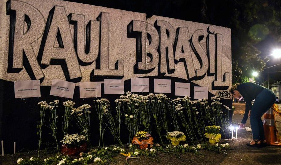 ‘Copycat Effect’: A tragédia de Suzano pode inspirar outras pessoas a fazer o mesmo? Uma mulher acende uma vela em frente à escola pública Raul Brasil. (Foto de NELSON ALMEIDA / AFP)