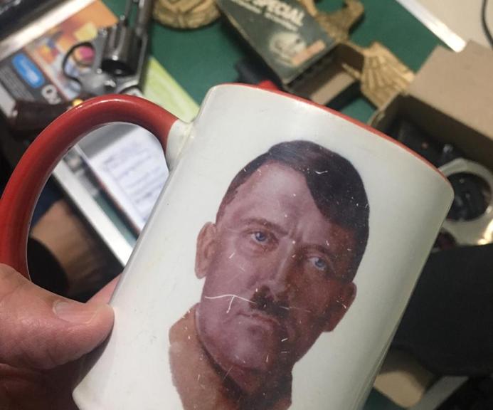 Caneca com o rosto de Adolf Hitler é um dos objetos apreendidos na casa em Ponta Grossa. | Polícia Civil/