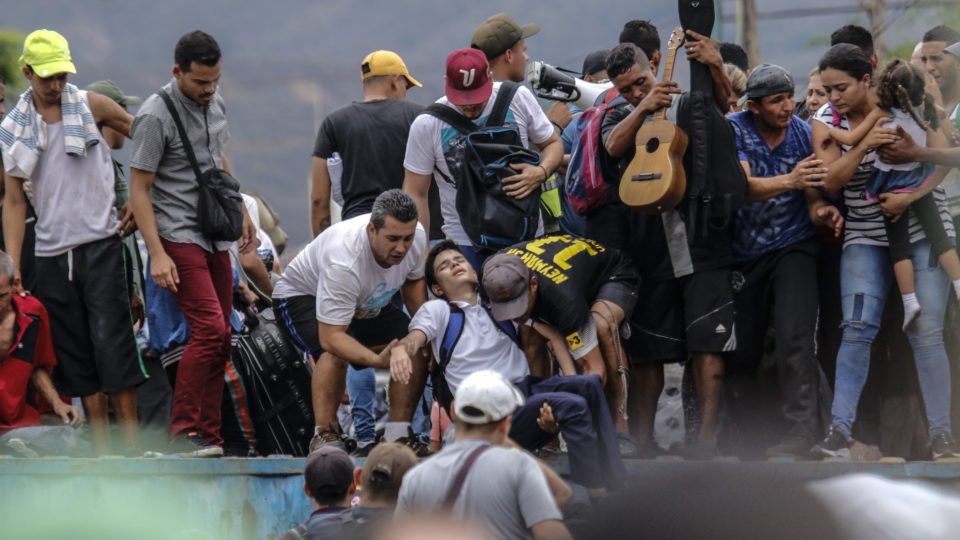 Venezuelanos ajudam um estudante que desmaiou ao tentar passar pela ponte Simon Bolívar, bloqueada pelos militares venezuelanos | Foto: Schneyder MENDOZA / AFP