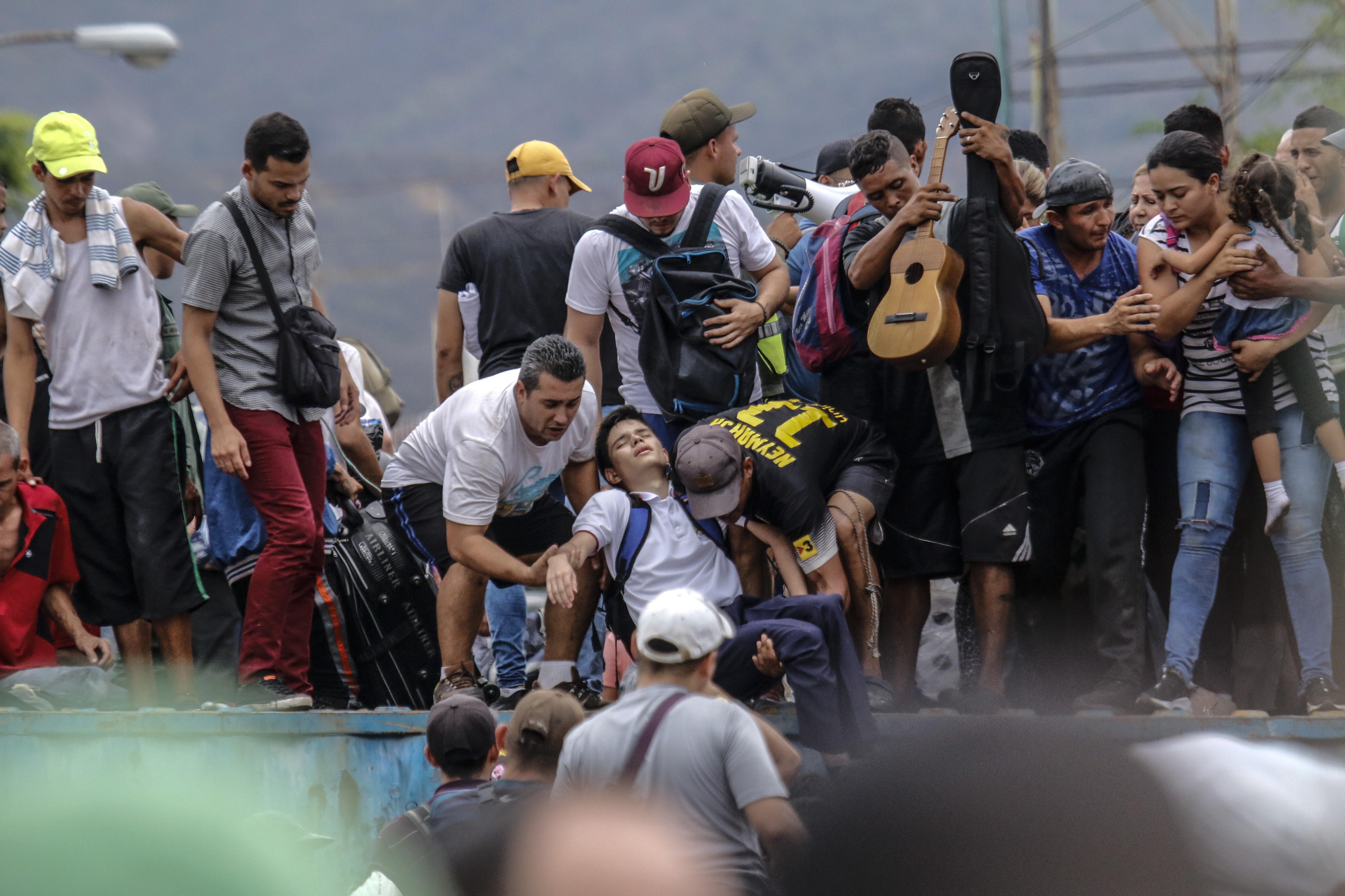 Venezuelanos ajudam um estudante que desmaiou ao tentar passar pela ponte Simon Bolívar, bloqueada pelos militares venezuelanos | Foto: Schneyder MENDOZA / AFP