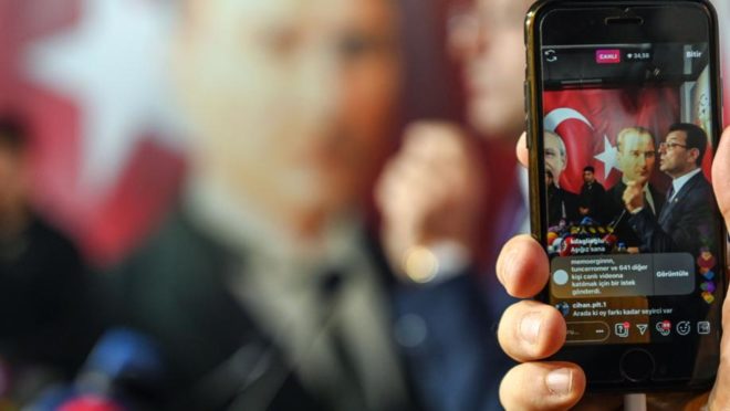 Ekrem Imamoglu, candidato do principal partido de oposição da Turquia (CHP), que saiu vitorioso na disputa pela prefeitura de Istambul, é visto por uma tela de celular durante uma coletiva de imprensa no comitê do CHP, em 3 de abril. Foto: Ozan Kose / AFP