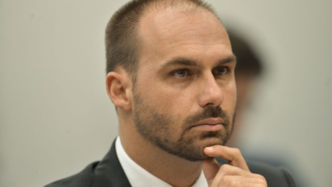 Eduardo Bolsonaro com a mão no queixo.
