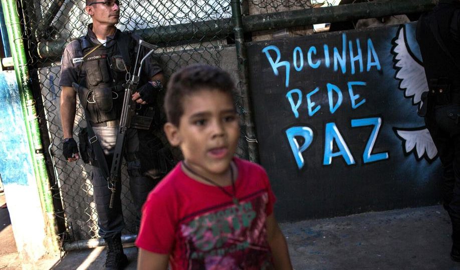 Uma criança passa enquanto um Policial militar vigia favela da Rocinha, no Rio de Janeiro, Brasil (26 de setembro de 2017). (FOTO: Mauro PIMENTEL/AFP)