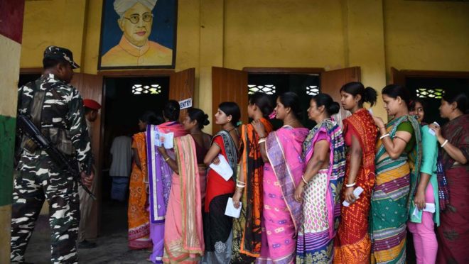 Eleitoras indianas formam fila para votar enquanto guardas fazem a segurança na vila Amoni, durante as eleições gerais da Índia, em 11 de abril. Foto: Biju Boro / AFP