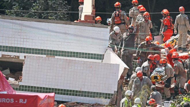 Bombeiros resgatam vítima do desabamento de dois prédios na comunidade da Muzema, no Rio. Foto: Carl de Souza/AFP