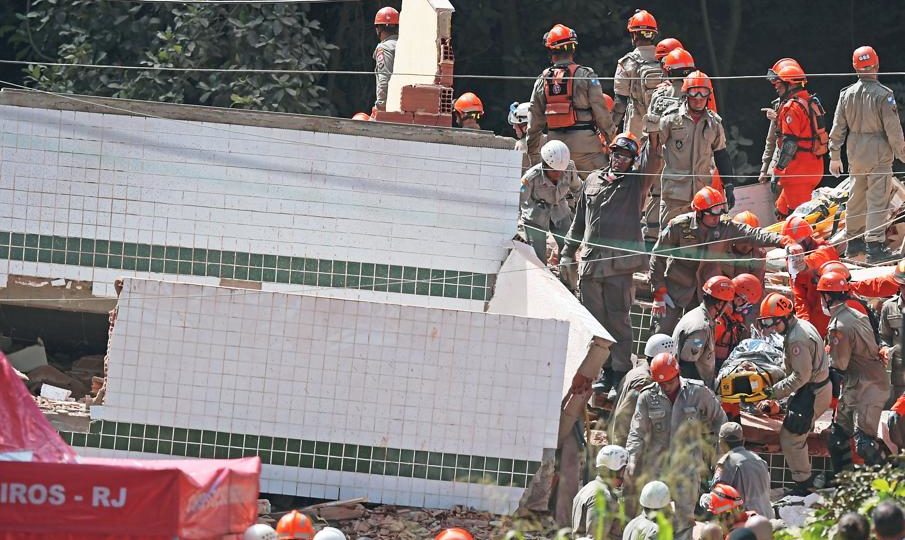 Bombeiros resgatam vítima do desabamento de dois prédios na comunidade da Muzema, no Rio. Foto: Carl de Souza/AFP