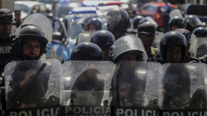Polícia de choque ao lado de um estacionamento onde manifestantes da oposição protestam contra o governo, em 17 de abril de 2019 | Foto: INTI OCON / AFP
