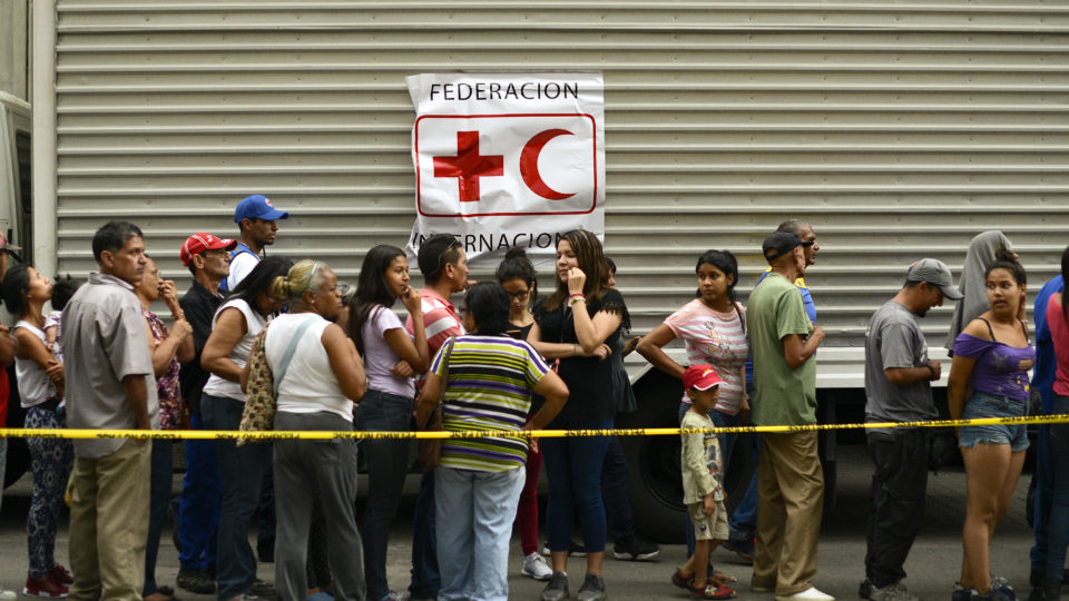 Fila de pessoas para receber água da Cruz Vermelha em Caracas na Venezuela.