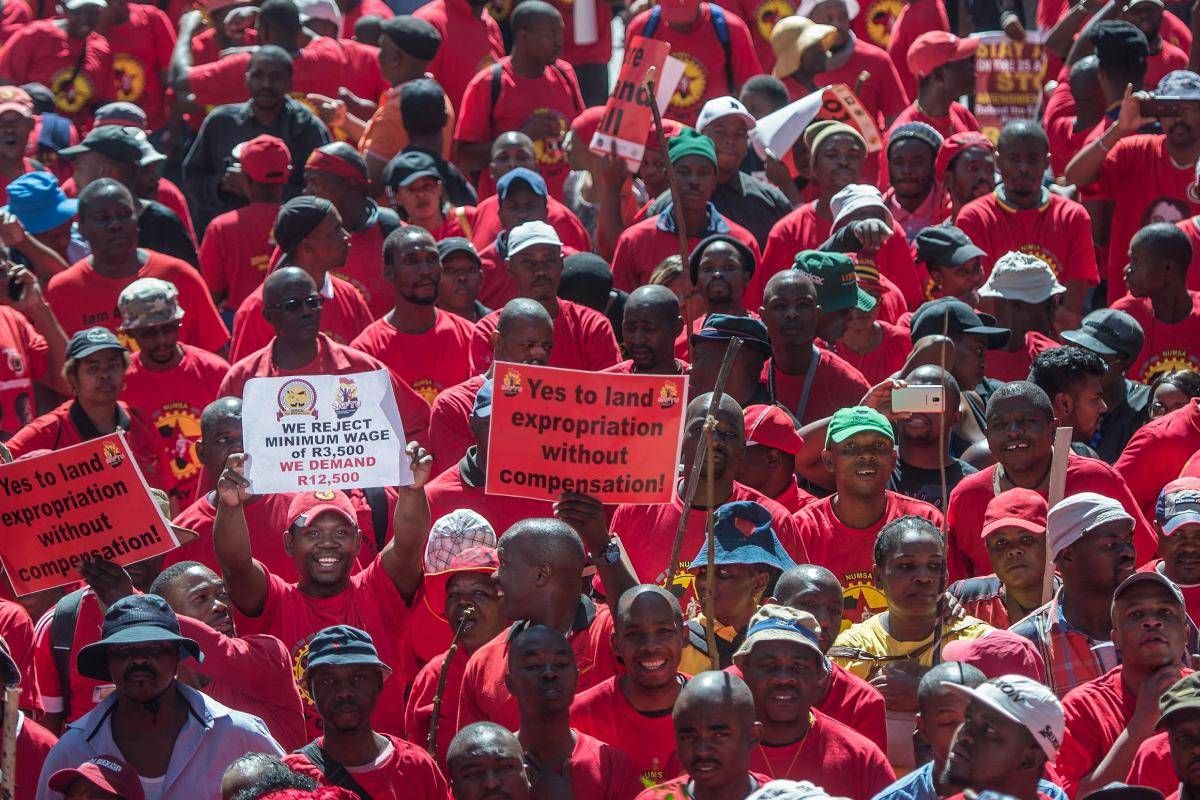 Membros da Federação Sul-Africana de Sindicatos, em marcha pela Cidade do Cabo durante greve geral, seguram cartaz onde se lê “sim para a expropriação de terras sem compensação”. | Mujahid Safodien/ AFP