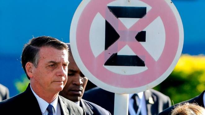O presidente Jair Bolsonaro ao lado de uma placa de trânsito (proibido parar e estacionar)
