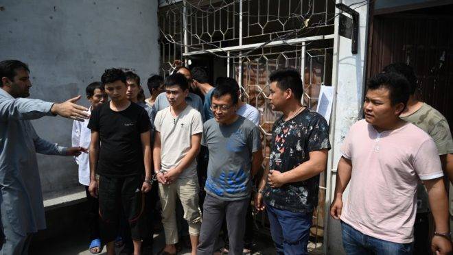 Um funcionário da Agência Federal de Investigação do Paquistão leva cidadãos chineses detidos e algemados para comparecer perante um tribunal por suposto envolvimento em uma rede de tráfico para atrair mulheres do Paquistão para casamentos falsos, forçando-as à prostituição na China, em Islamabad, em 9 de maio de 2019. O Paquistão prendeu pelo menos oito cidadãos chineses por supostamente atrair jovens paquistanesas para casamentos falsos e depois forçá-las à prostituição na China, confirmaram as autoridades à AFP em 7 de maio.