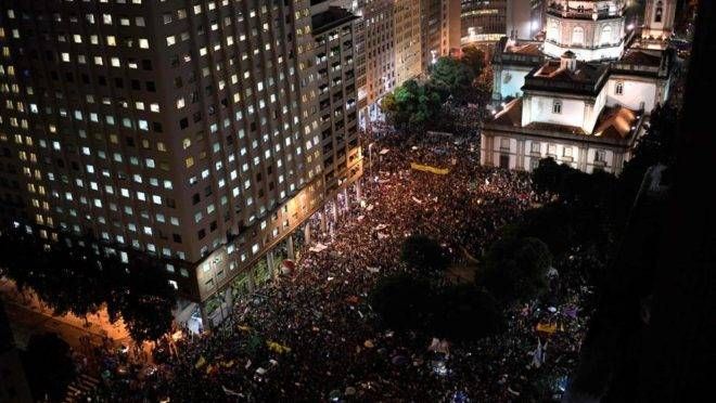 A imagem mostra milhares de pessoas nas ruas do Rio de Janeiro em protesto contra bloqueios no orçamento da Educação.