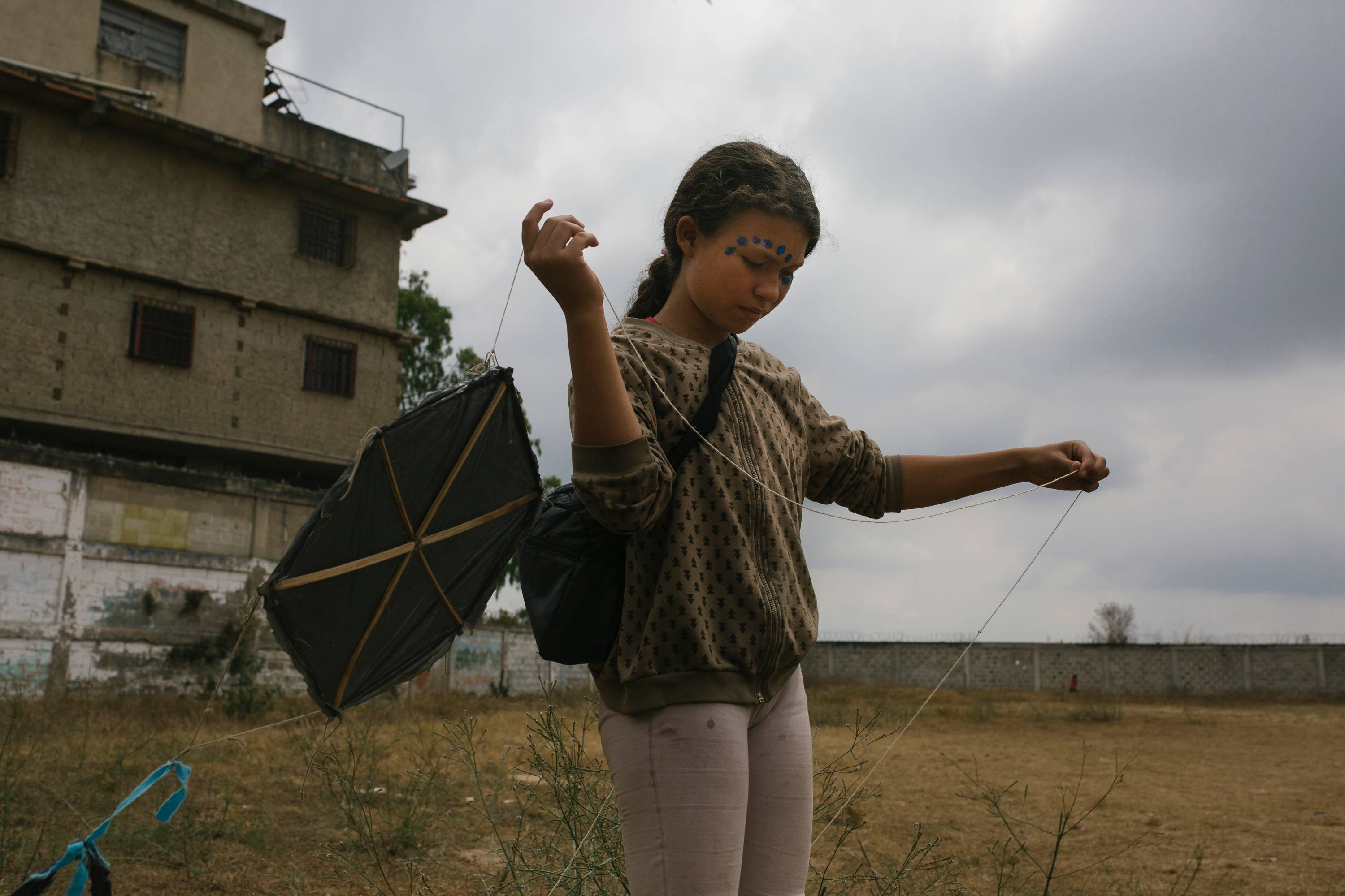 Menina brinca com uma pipa no pátio da escola San Alberto Hurtado em La Vega, Caracas, Venezuela, 16 de abril