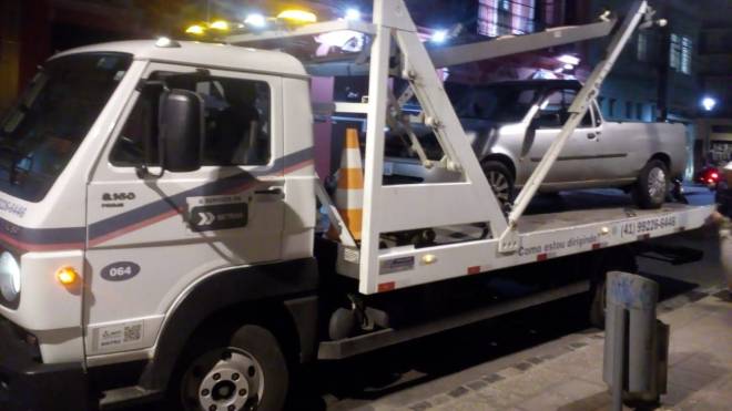 Carro Ford Courier sendo rebocado no Centro de Curitiba por acumular R$ 438,6 mil em dívida de multas e impostos.