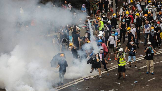Manifestante joga uma bomba de gás lacrimogêneo disparada pela polícia durante uma manifestação em Hong Kong