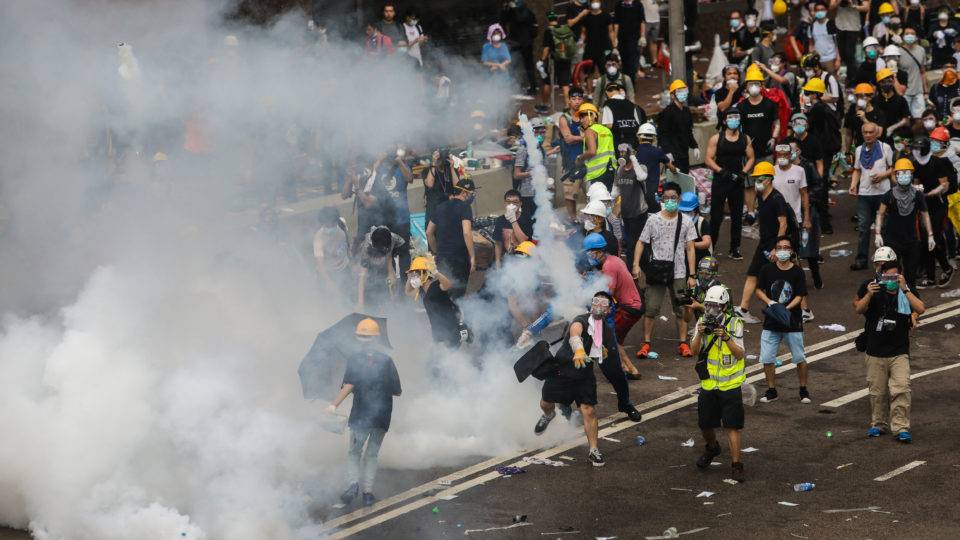 Manifestante joga uma bomba de gás lacrimogêneo disparada pela polícia durante uma manifestação em Hong Kong