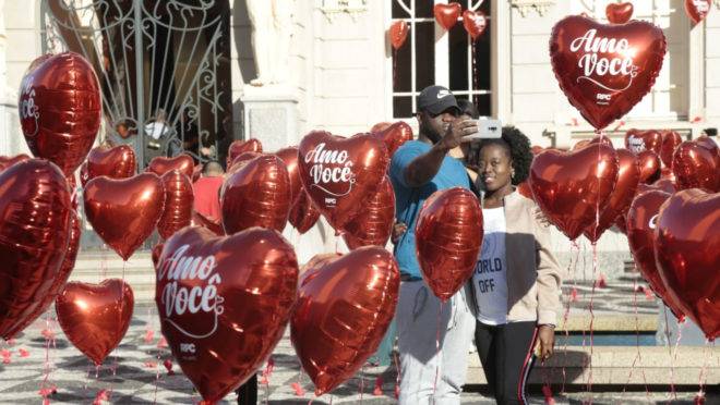 Casal tirando foto em meio a balões em forma de coração