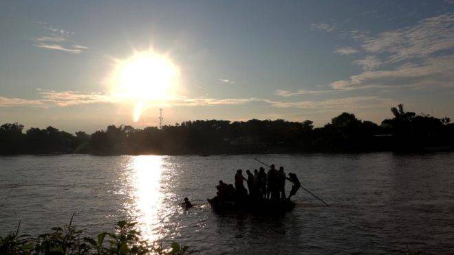Migrantes e residentes usam um bote improvisado para atravessar ilegalmente o Rio Suchiate, de Tecum Uman, Guatemala, para Ciudad Hidalgo, México, em 14 de junho