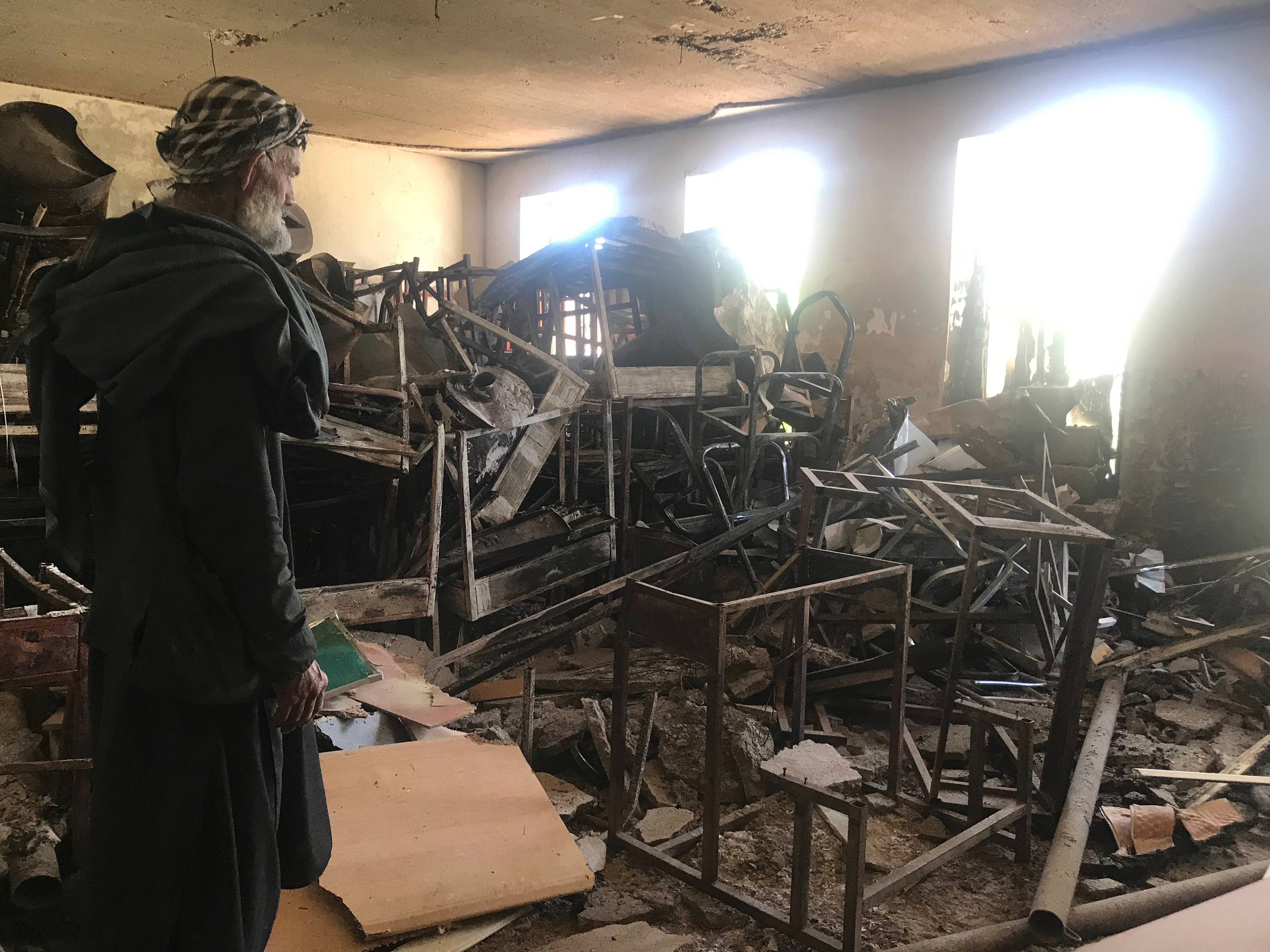 Um segurança olha carteiras danificadas e destroços no interior da escola para meninas Sher Ali Khan em Naw Deh, na província de Farah, Afeganistão, em abril de 2019. Dois ataques a bomba no Afeganistão renovaram os temores de uma volta da repressão caso o Talibã se torne parte de um governo futuro