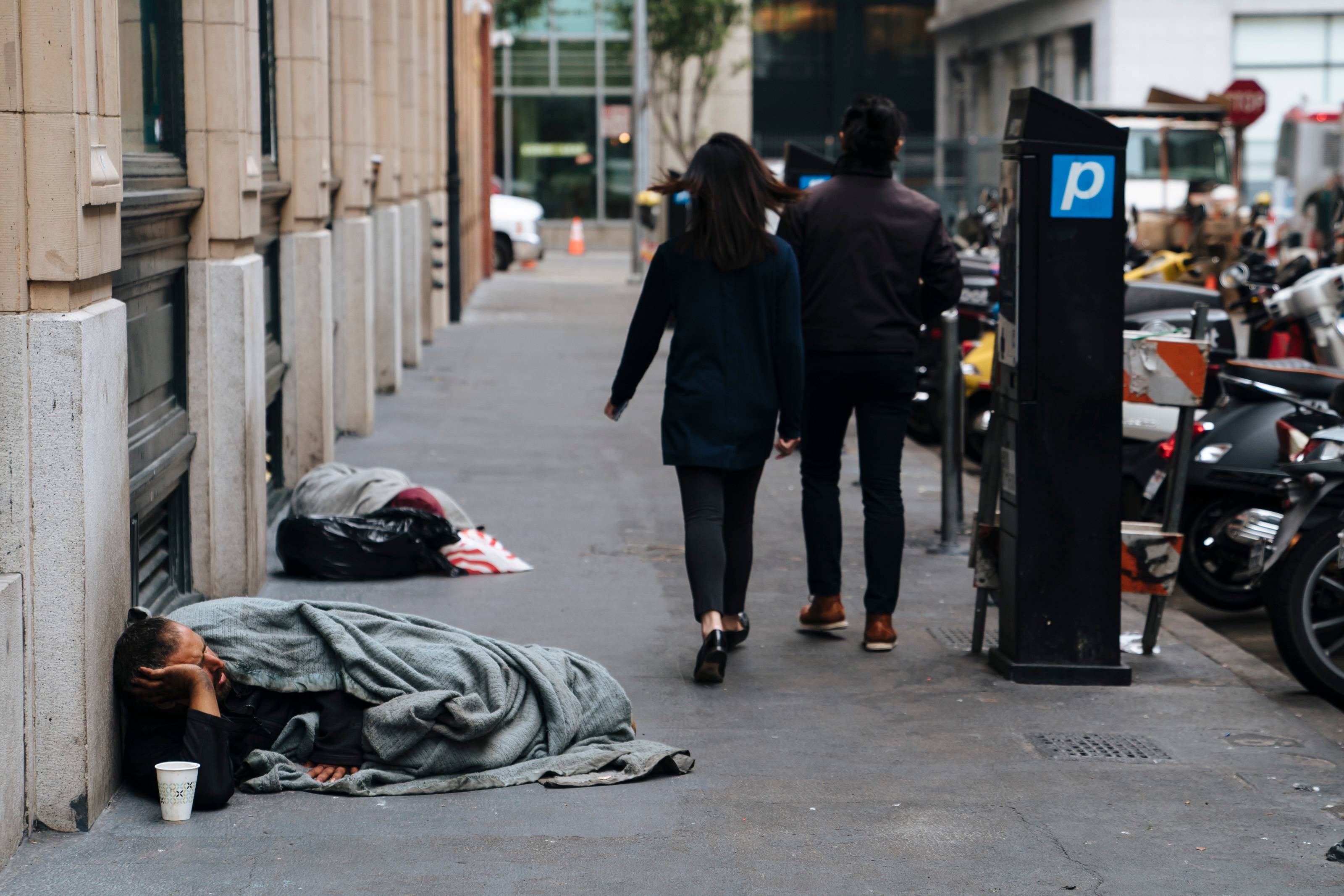 Pedestres caminham por moradores de rua que dormem nas calçadas de San Francisco.
