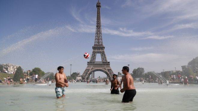 Pessoas se banham em frente à Torre Eiffrel
