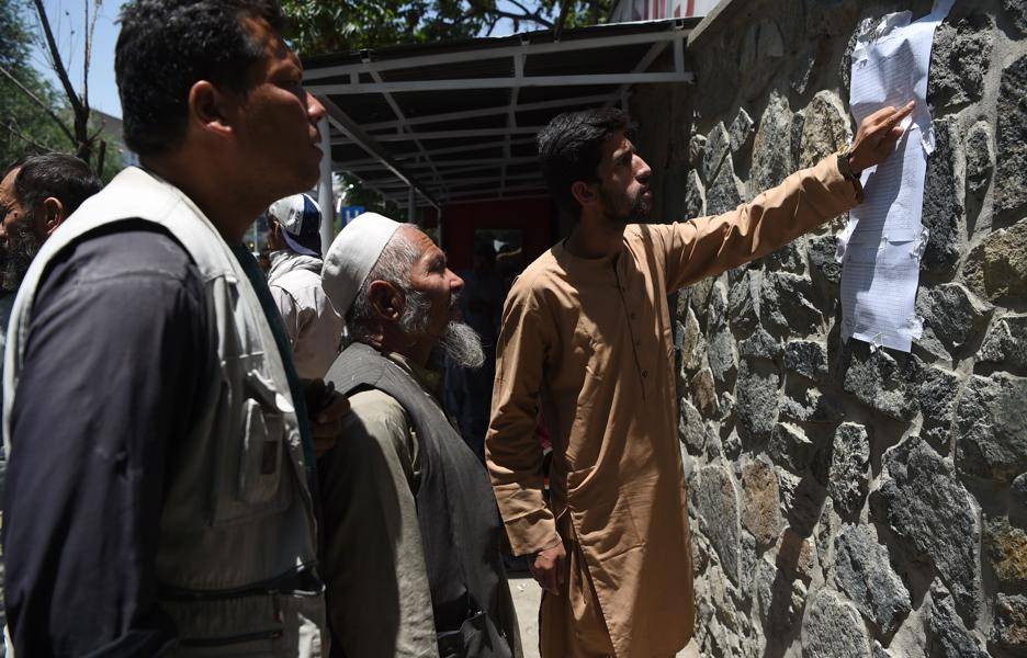 Afegãos conferem uma lista com os nomes das vítimas de um atentado do Talibã no centro de Cabul, em frente a um hospital de uma organização humanitária italiana